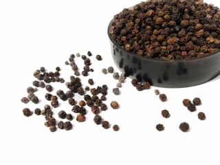 Dry Black peppercorns in bowl on white background sideview .