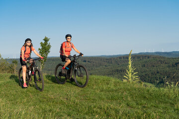 Fototapeta premium Grandmother with electric mountain bike and granddaughhter without electric help on a smooth meadow trail in the Franconian Switzerland area of Bavaria, Gemany