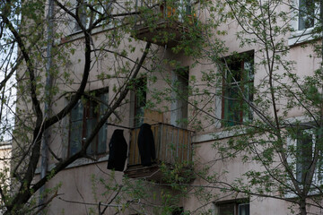 filled frame day shot of two black coats and jackets hanging and drying in the sun on a balcony of...