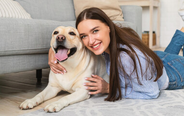 Young happy woman with dog lying on floor