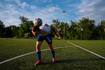 Young male soccer player juggles a ball on a soccer field