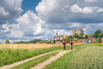 grandmother and granddaughter riding their mountain bikes in front of the awesome skyline of Hiltpoltstein in Frankonian Switzerland, Bavaria, Germany