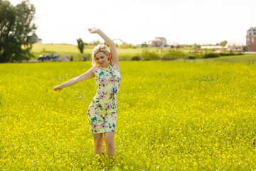 Fototapeta premium Young woman with her arms wide spread is enjoying in the sunny summer day, rear view