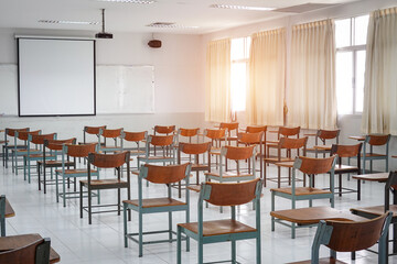 Fototapeta na wymiar Empty classroom with vintage tone wooden chairs. Classroom arrangement in social distancing concept to prevent COVID-19 pandemic. Back to school concept. 