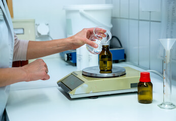female pharmacist mixing chemical liquids on medical scales in a laboratory