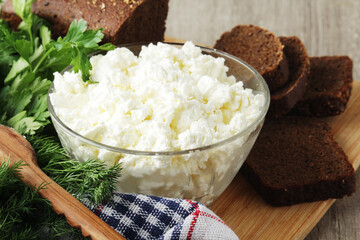 A bowl with cottage cheese, a bunch of green and rye bread