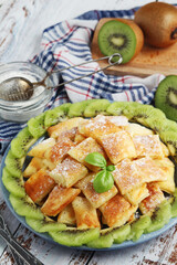Austrian dessert Kaiserschmarrn served with sugar powder and kiwi fruit
