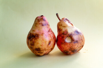 Over ripe green delicious pear against yellow background. Zero waste and organic food concept
