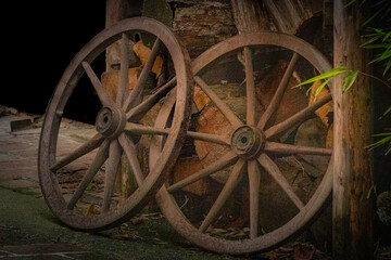 Fototapeta na wymiar two old wagon wheels leaning on a wood pile