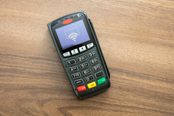Payment machine, POS terminal on wooden background.