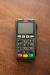 Payment machine, POS terminal on wooden background.