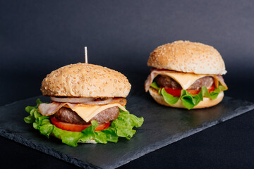 View of fresh tasty burgers on black board