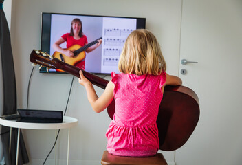 little girl having guitar lesson online at home