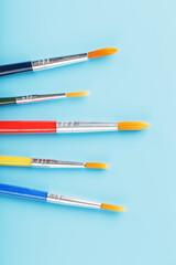 Brushes of different colors for drawing, creativity and art on a blue background.