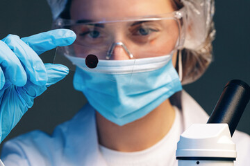 Woman scientist looking at slide with blood sample near microscope in laboratory