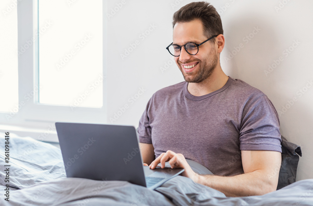 Aufkleber man using laptop browsing internet sitting in bed at home