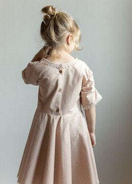 Little girl's back in beautiful dress. Children's clothing store. Handmade. Sale of children's dresses. Pastel dress for little princess.  Image with selective focus.