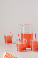 Summer refreshing grapefruit drink, jug and glasses with grapefruit pulp and juice and straws