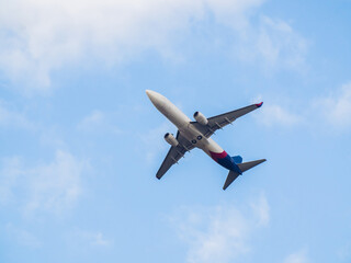 Passenger airplane takes off against the blue sky with clouds.