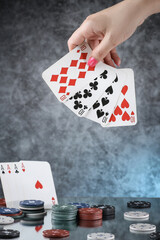 Close up of a woman hand holding poker playing cards, with cards of four aces on the background. Online gambling. Addiction.