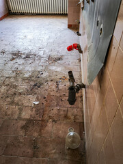 Water pipes out of the wall in destroyed room in old abandoned hospital