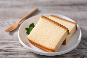 Castella (kasutera) - Delicious Japanese sliced sponge cake food on white plate over rustic wooden table, close up, healthy eating, copy space design.