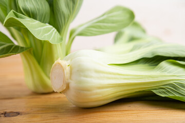 Fresh green bok choy or pac choi chinese cabbage on a brown wooden background. Side view, close up.