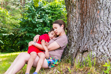 mother and son resting under a tree in the summer