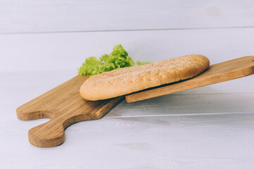 Pellet of bread with greens on a cutting board on a white table.