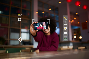 Selective focus on modern smartphone held by African American hipster girl taking photo for social network profile using application. Mobile phone camera with infographics interface