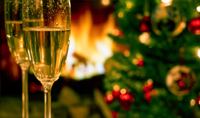 Champagne glasses on the background of Christmas tree and fireplace. New year celebration. Champagne glass close up.
