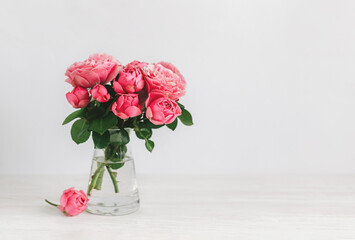 Romantic bouquet of pink roses in a glass vase on a white background.