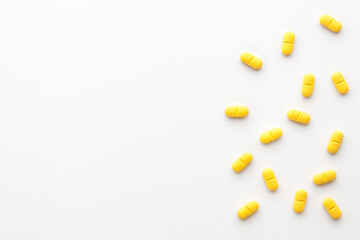 Yellow pills scattered on a white background. Copy space.