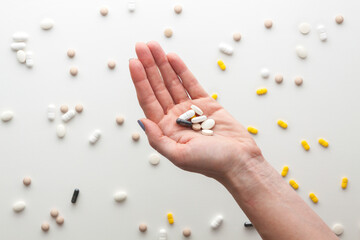 Female hand with pills isolated on white. Randomly scattered tablets.