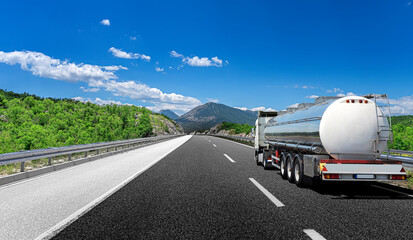 big fuel gas tanker truck on highway against the backdrop of a mountain landscape.