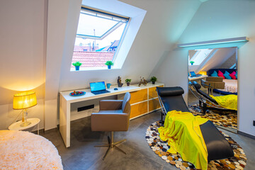 Loft interior of bedroom in modern apartment. Roof window. Place to work. Lounge chair. Huge mirror. Home decor.