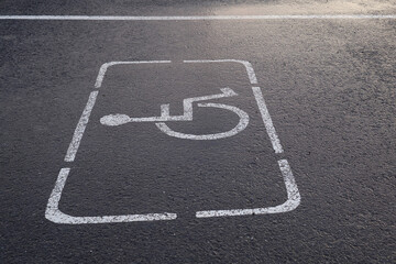 Parking lot with painted sign of wheelchair on asphalt, parking spaces for disabled visitors. Disabled parking spaces.