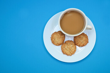 Top view of a cup of coffee and wheat cookies on blue background 