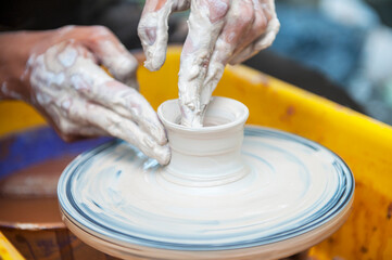 The potter makes pottery dishes on potter's wheel.