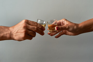Hands with shot glasses toasting. Concept of alcoholism and addiction. - obrazy, fototapety, plakaty