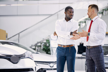 confident professional salesman talk about characteristics of car to customer man, black business...