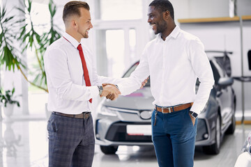 caucasian dealer shaking hands to customer in auto salon. auto business, car sale, deal, gesture and people concept