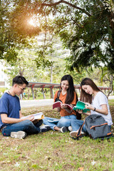 Happy young Asian young group of man and woman students are sitting during reading books in the park at university, Education concept, Education back to university concept