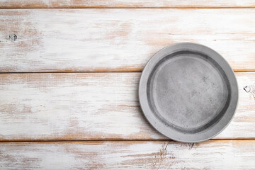 Empty gray ceramic plate on white wooden background. Top view, copy space.