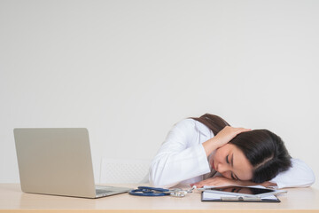 Young Asian woman doctor sitting on desk, she look unhappy and tired because of overwork, Concept of stressed exhausted and doctor liability, Dealing with frustrated