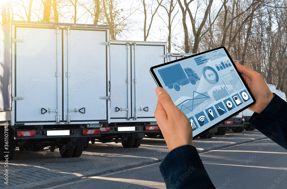 Aufkleber manager with a digital tablet on the background of trucks. fleet management