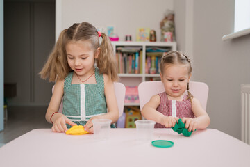 Little girls with lovely faces play with clay molding shapes, learning through playing with colored plasticine developing creativity