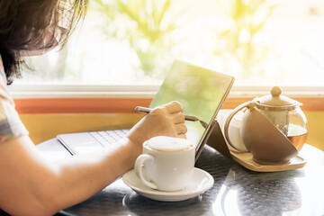 Quarantined woman work from home by using a tablet and stress relief with hot coffee. New normal lifestyle. Selective focus