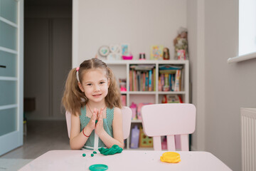 Little girl with a lovely face play with clay molding shapes, learning through playing with colored plasticine developing creativity