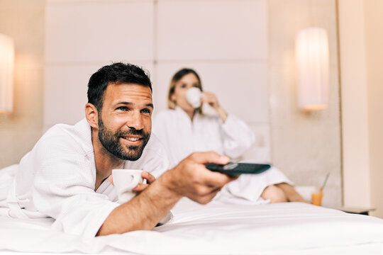 Couple Drinking Coffee And Watching TV In A Hotel Room